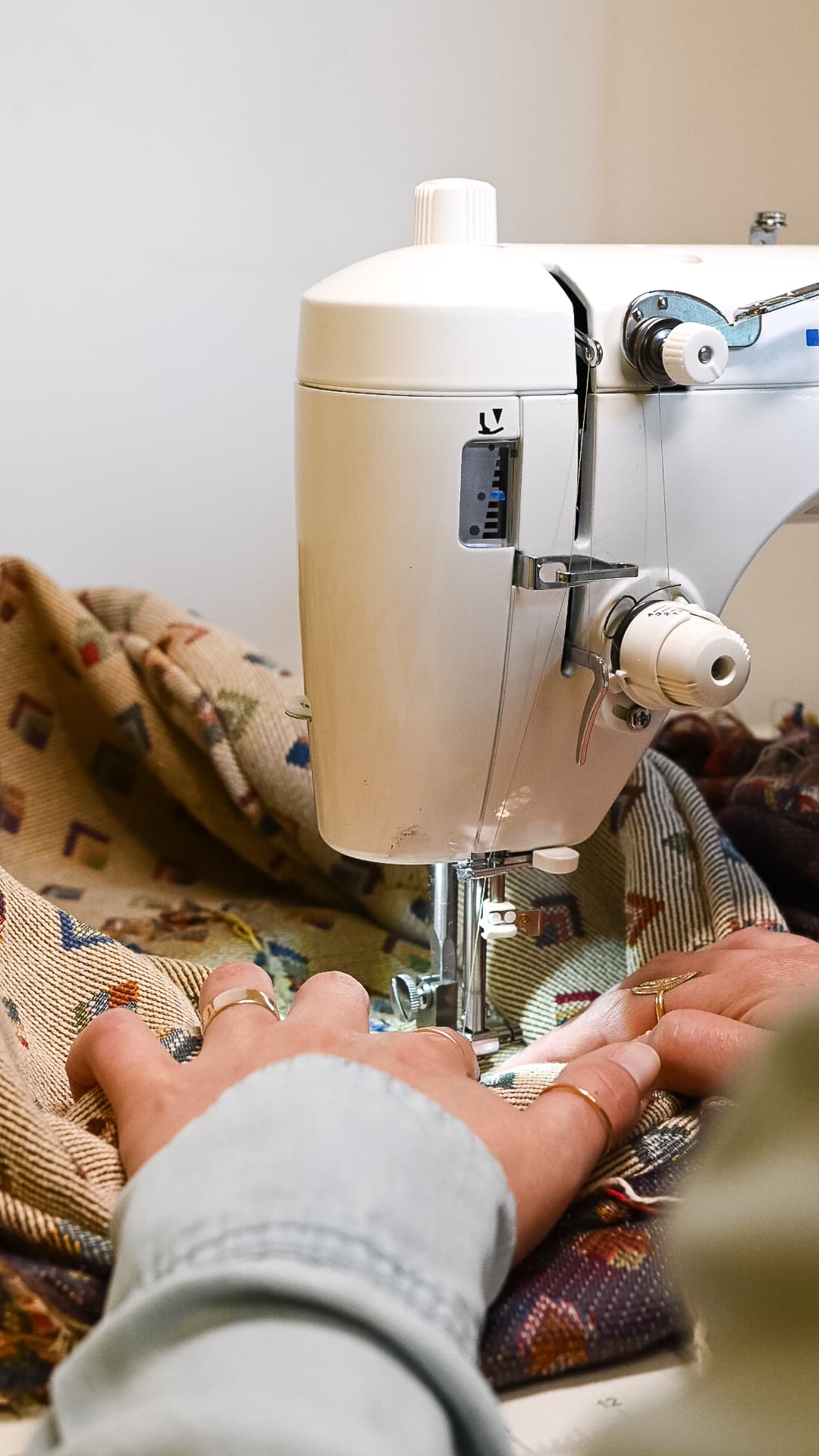 Hands guiding a patterned fabric under the needle of a sewing machine.